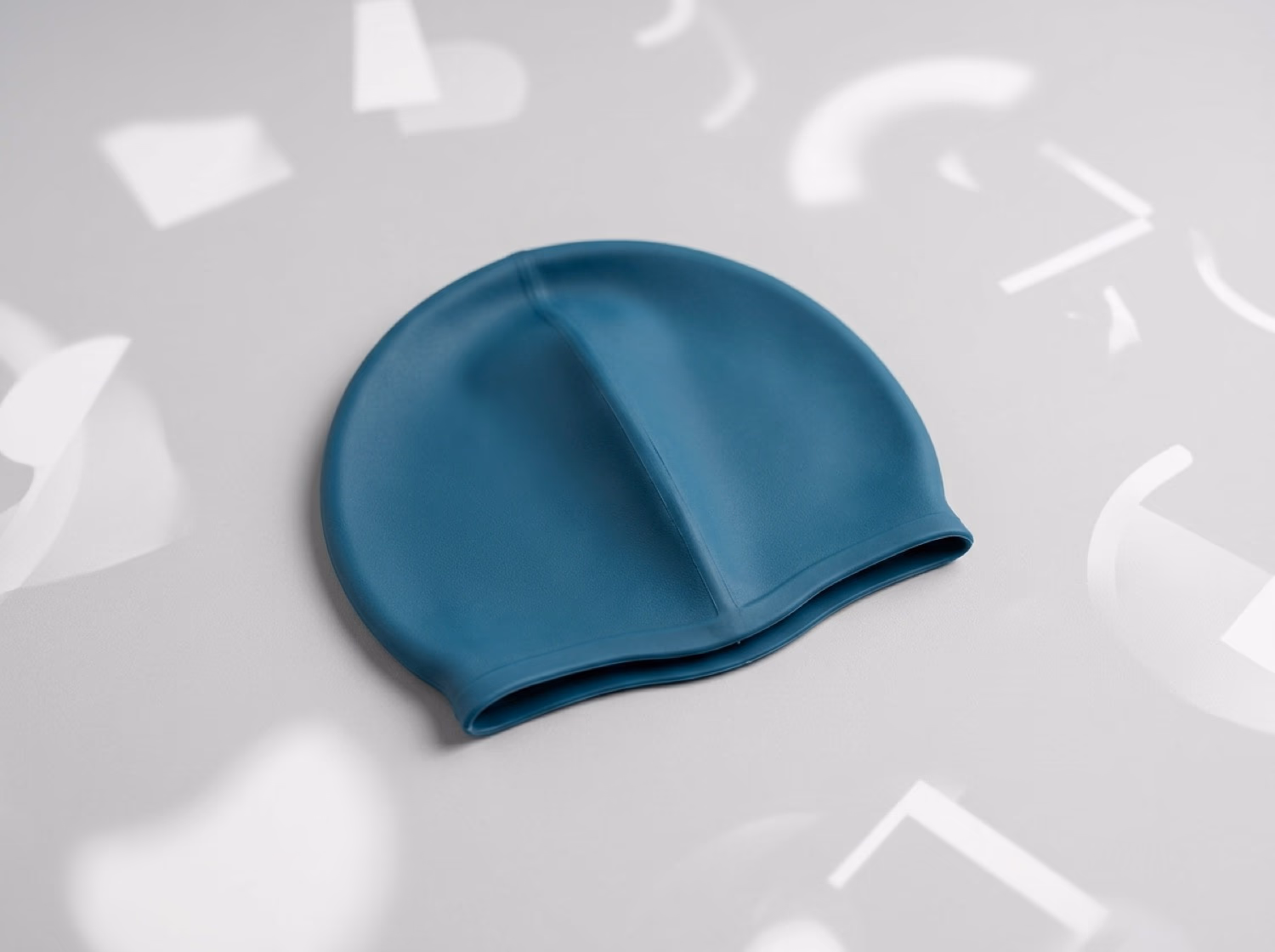 Petrol-blaue Latex-Badekappe für Schwimmvereine auf hellem Studio-Untergrund